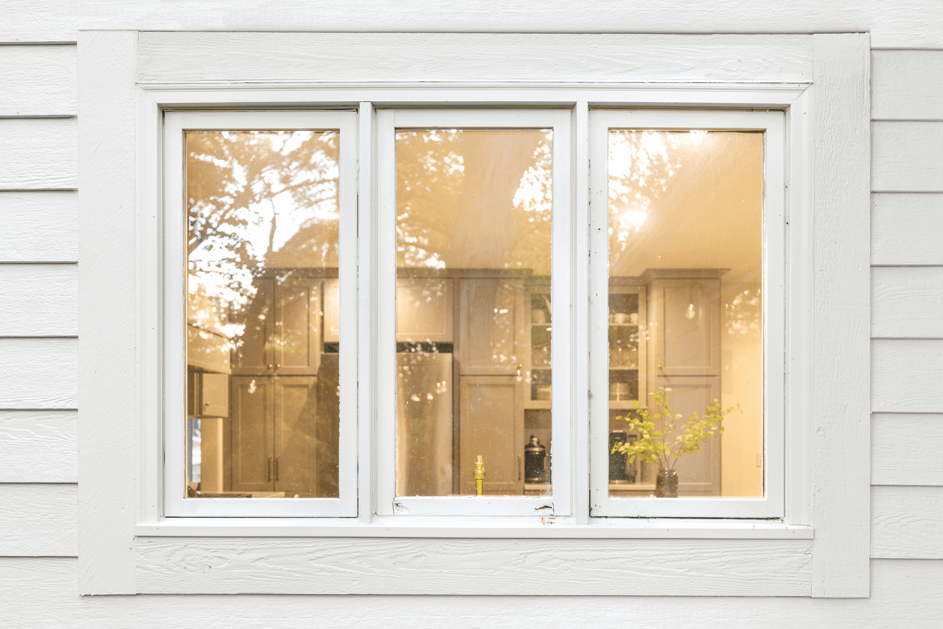 Old, drafty triple-pane window with dated white frame before replacement
